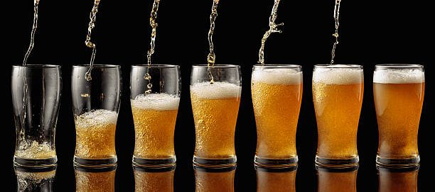 Welcome to Beer & Hops pouring beer into a glass. glass of beer on a black background.